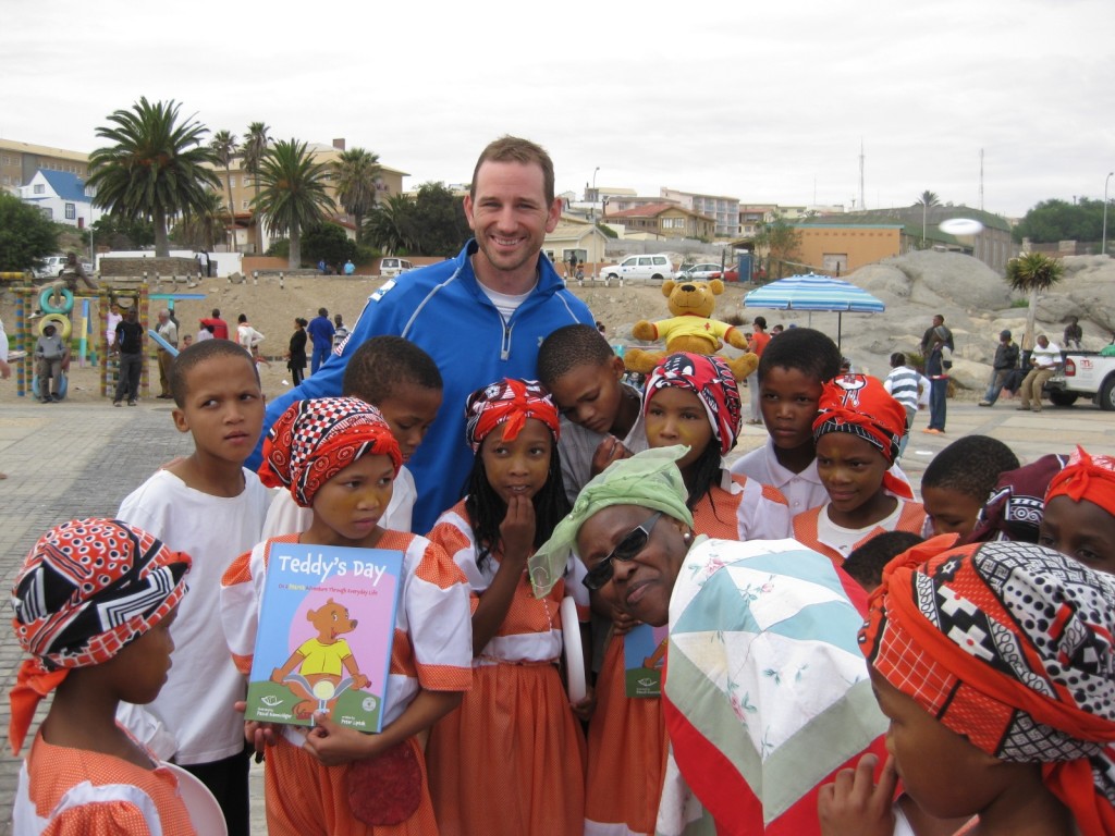 Peter Liptak posing with children of Namibia holding Teddy's Day